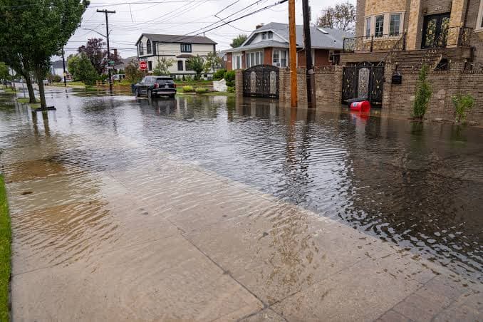 A house-lined street and sidewalk underwater in Queens