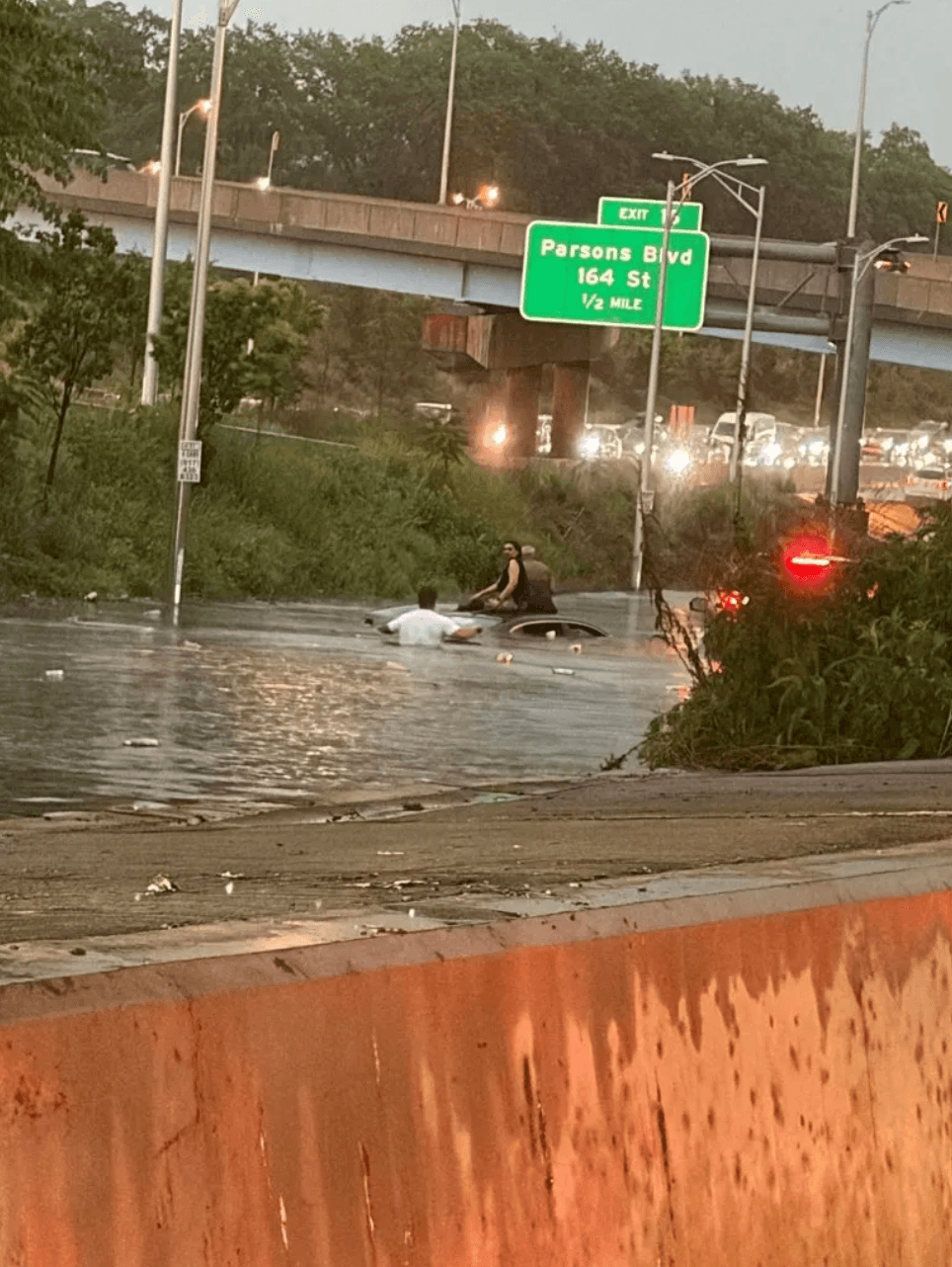 People helping a driver trapped in a flooded car on the Jackie Robinson Parkway (via NY Post)